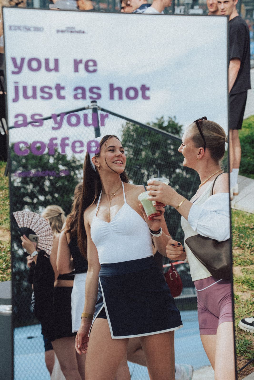 Guests with Eduscho cups in front of the 'you're just as hot as your coffee' sign